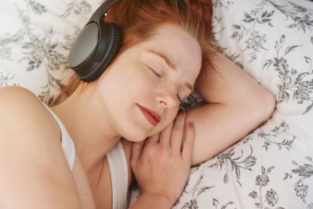 A person sleeping with headphones on, listening to sleep music